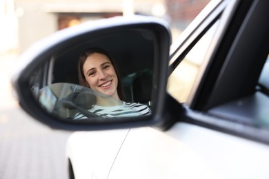 Photo of Driver driving modern auto, view through car side mirror