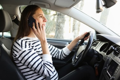 Photo of Driver talking on smartphone while driving modern car