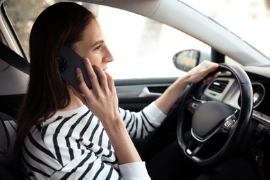 Photo of Driver talking on smartphone while driving modern car