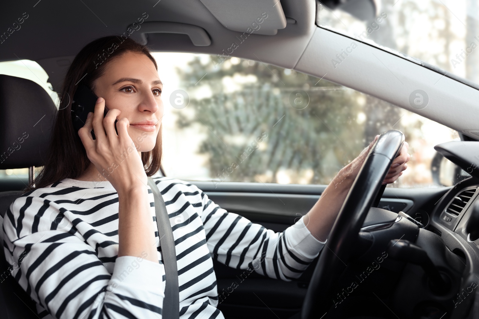 Photo of Driver talking on smartphone while driving modern car