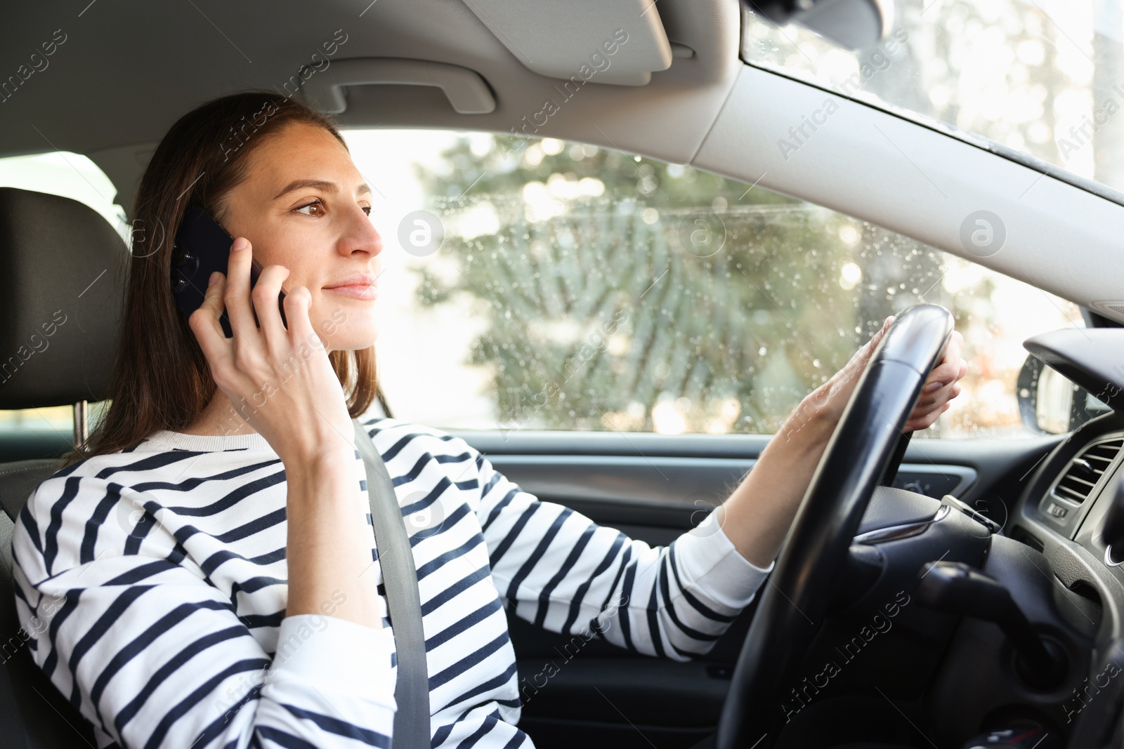 Photo of Driver talking on smartphone while driving modern car