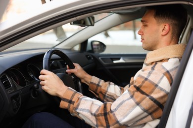 Photo of Driver behind steering wheel of modern car, view from outside