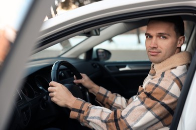 Photo of Driver behind steering wheel of modern car, view from outside