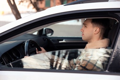 Photo of Driver behind steering wheel of modern car, view from outside