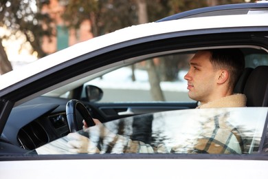 Photo of Driver behind steering wheel of modern car, view from outside