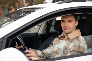 Photo of Driver behind steering wheel of modern car, view from outside