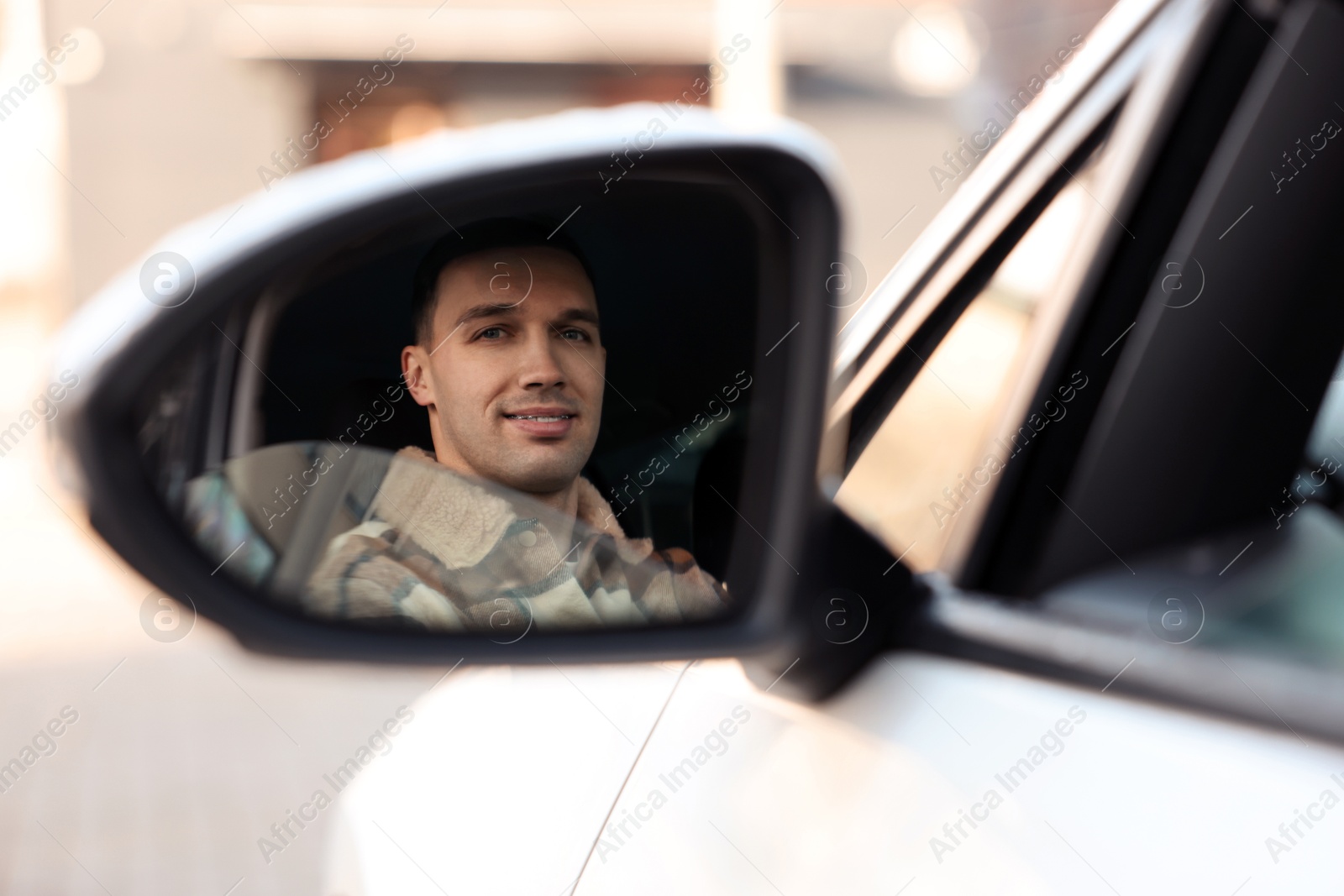 Photo of Driver driving modern auto, view through car side mirror