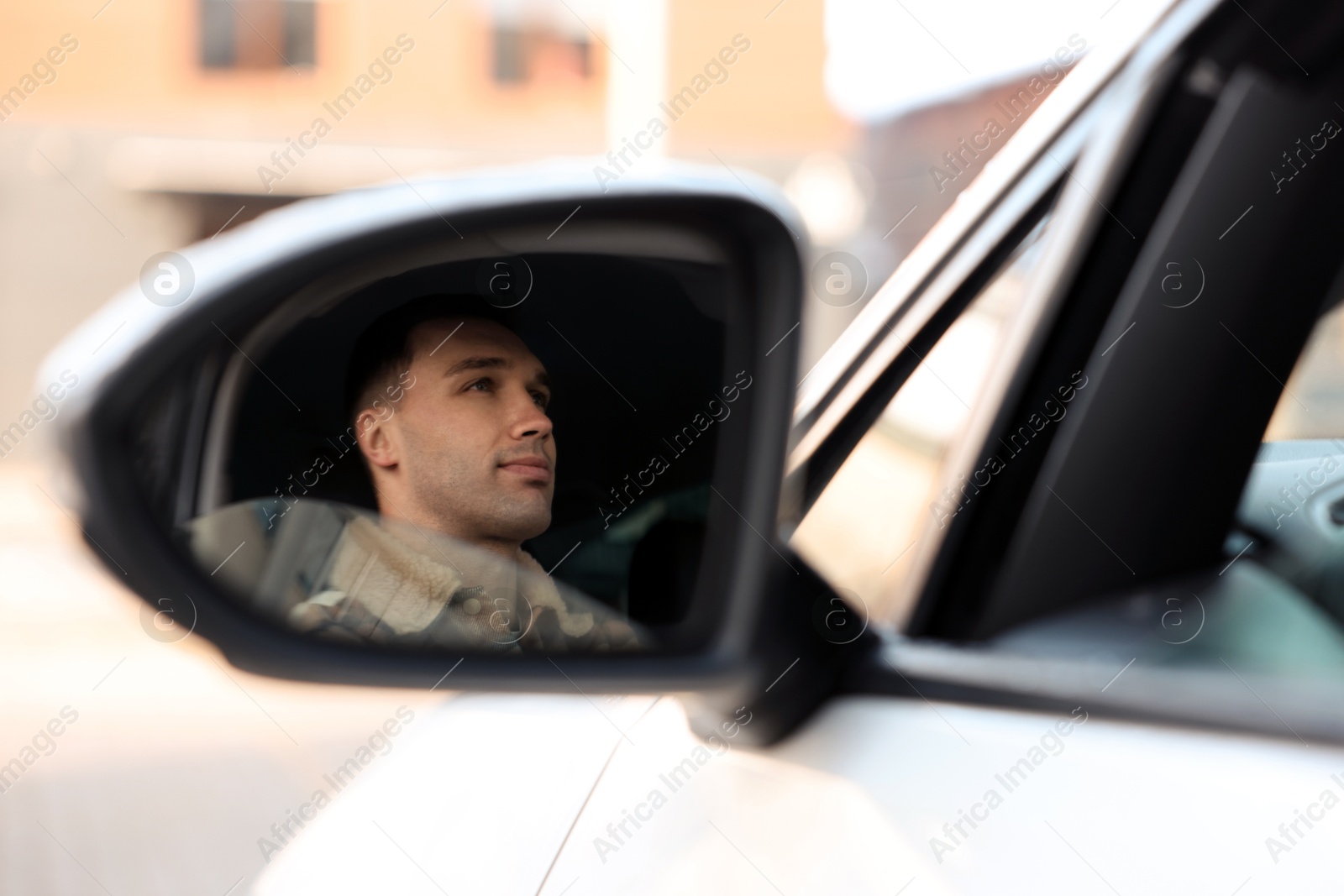 Photo of Driver driving modern auto, view through car side mirror