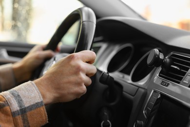 Photo of Driver holding steering wheel while driving car, closeup