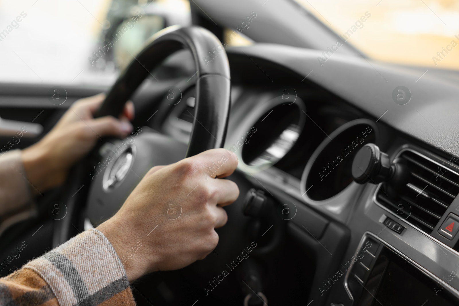 Photo of Driver holding steering wheel while driving car, closeup