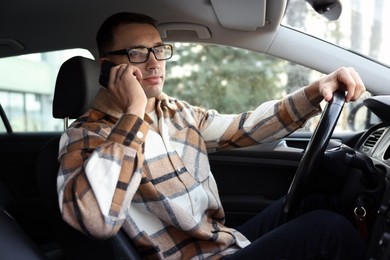 Photo of Driver talking on smartphone while driving modern car