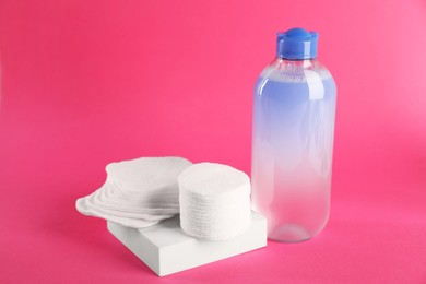 Photo of Clean cotton pads and micellar water on pink background. Space for text