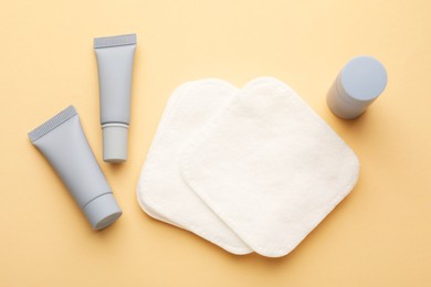 Photo of Clean cotton pads and cosmetic products on beige background, flat lay