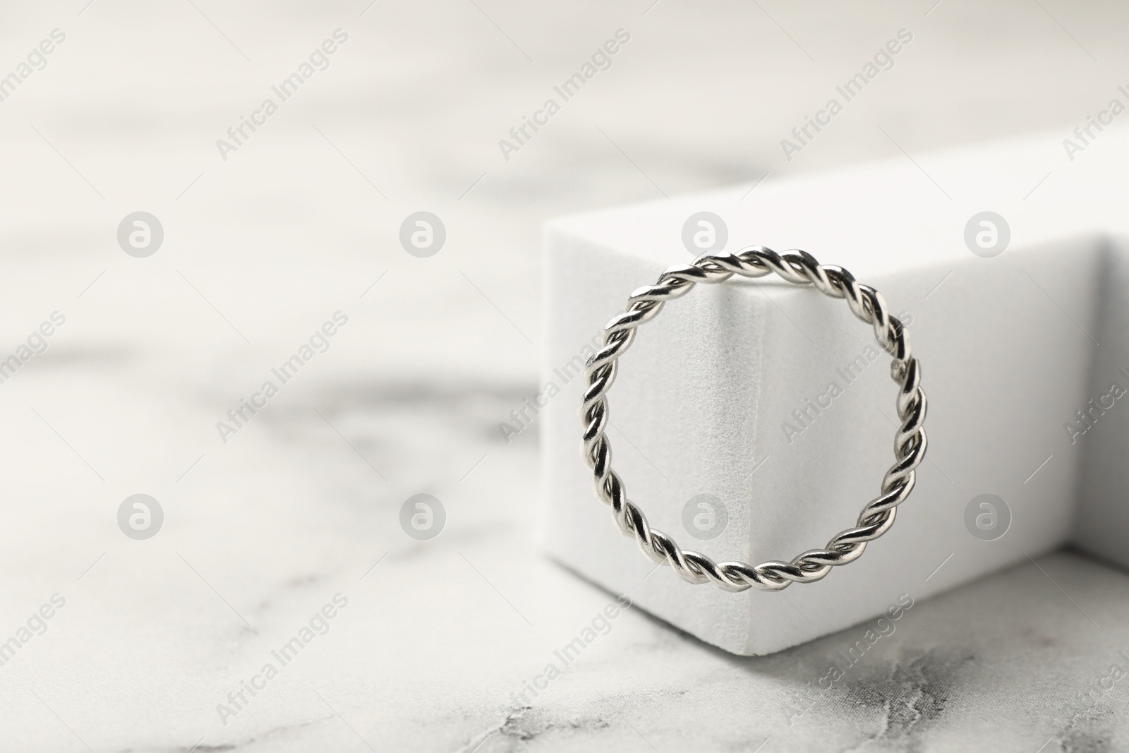 Stylish presentation of ring on white marble table, closeup. Space for text Photo of Stylish presentation of ring on white marble table, closeup. Space for text