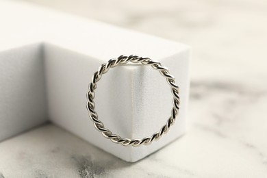 Photo of Stylish presentation of ring on white marble table, closeup