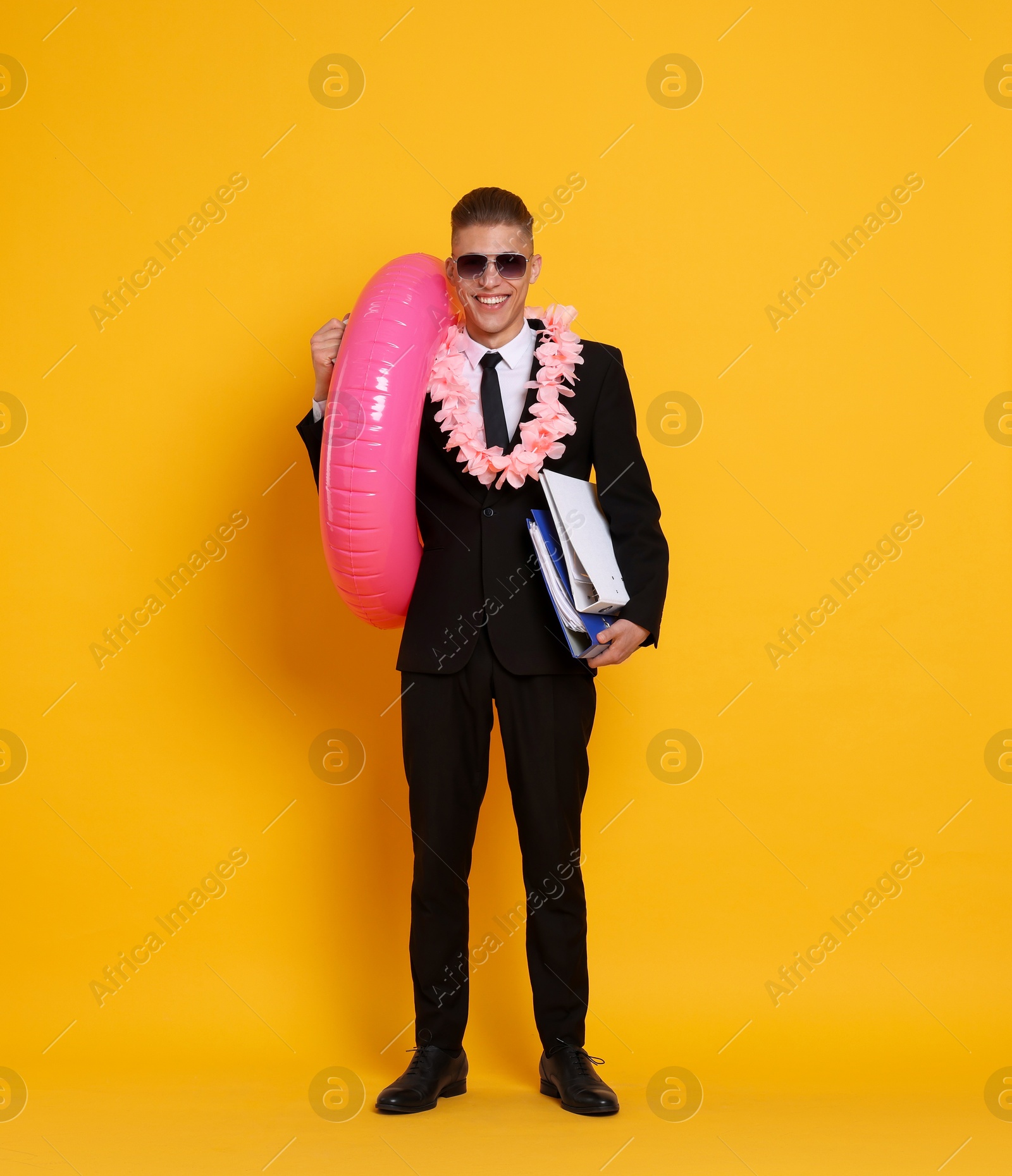 Photo of Businessman with folders, wreath of flowers and inflatable ring on orange background