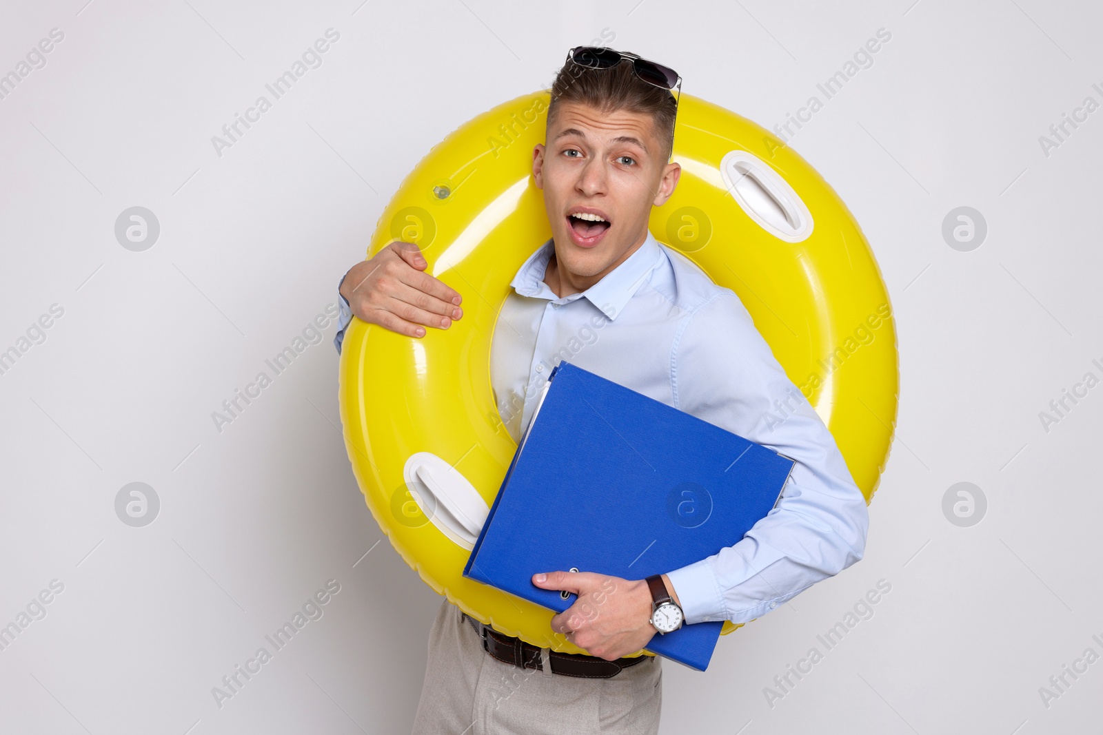 Photo of Businessman with inflatable ring and folder on white background