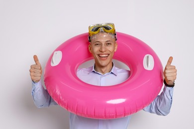 Photo of Businessman with inflatable ring and diving mask showing thumbs up on white background