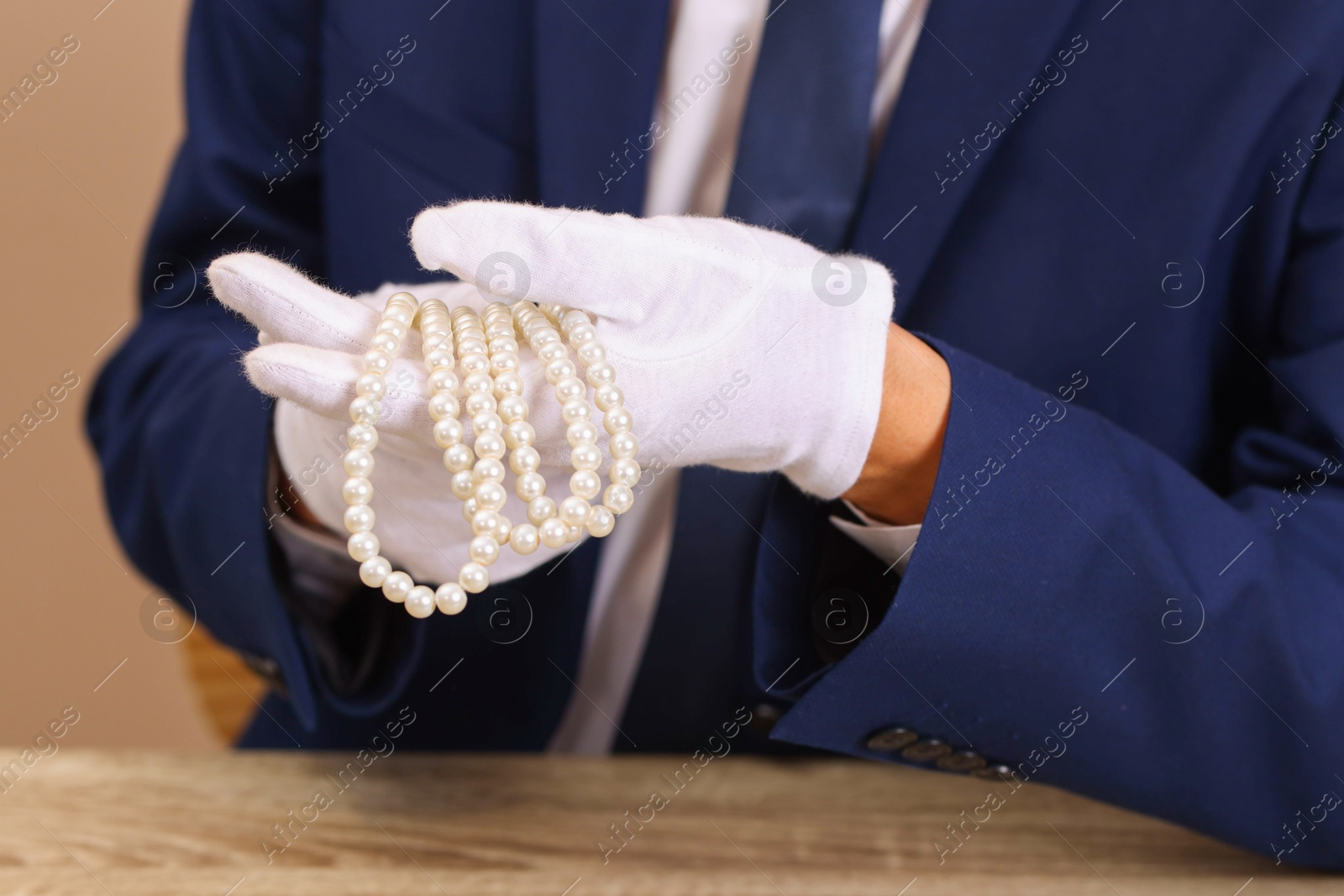 Photo of Appraiser with luxury jewelry at wooden table, closeup