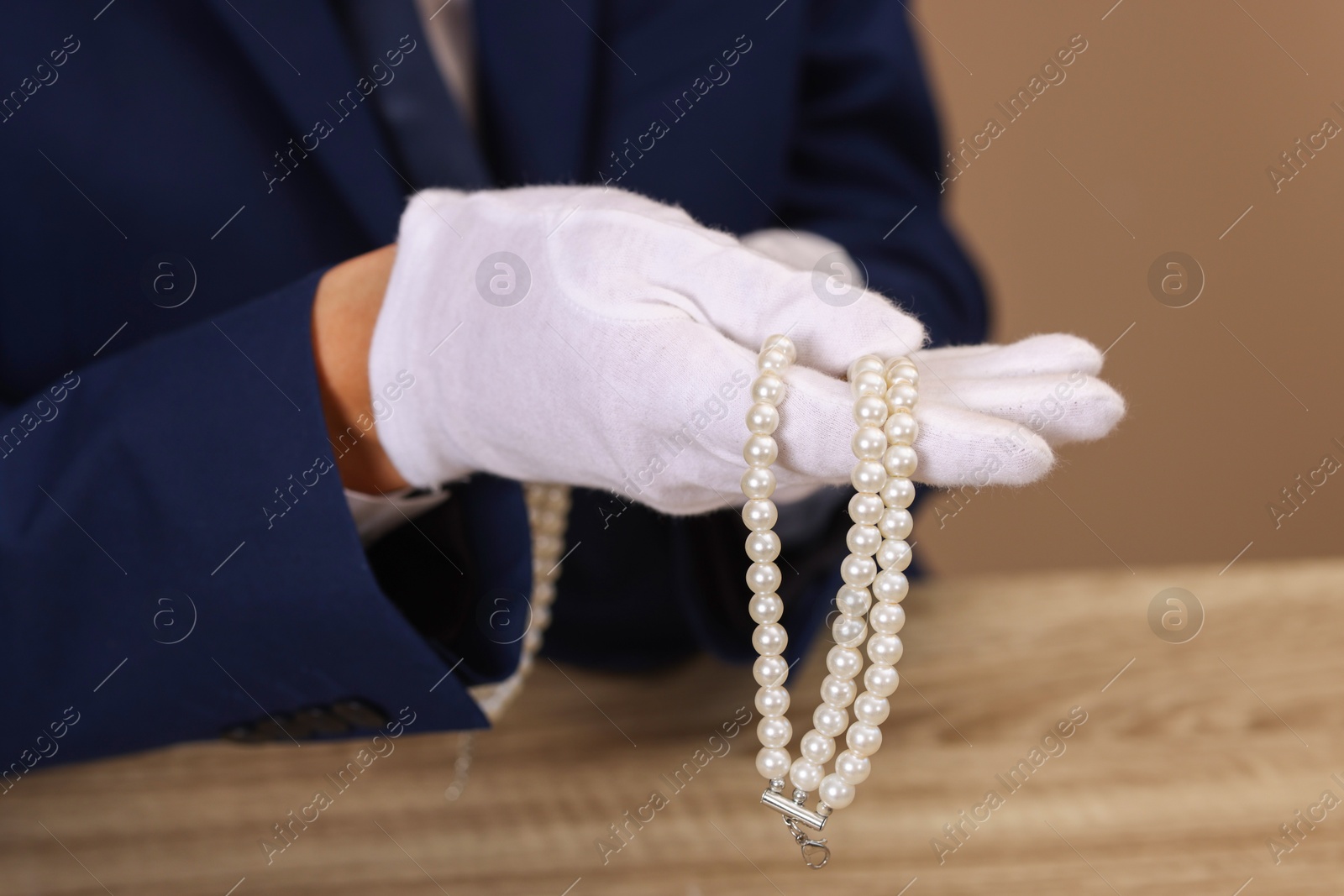 Photo of Appraiser with luxury jewelry at wooden table, closeup