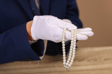 Photo of Appraiser with luxury jewelry at wooden table, closeup