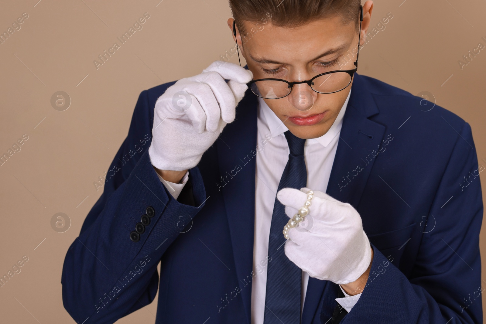 Photo of Appraiser evaluating luxury jewelry on beige background