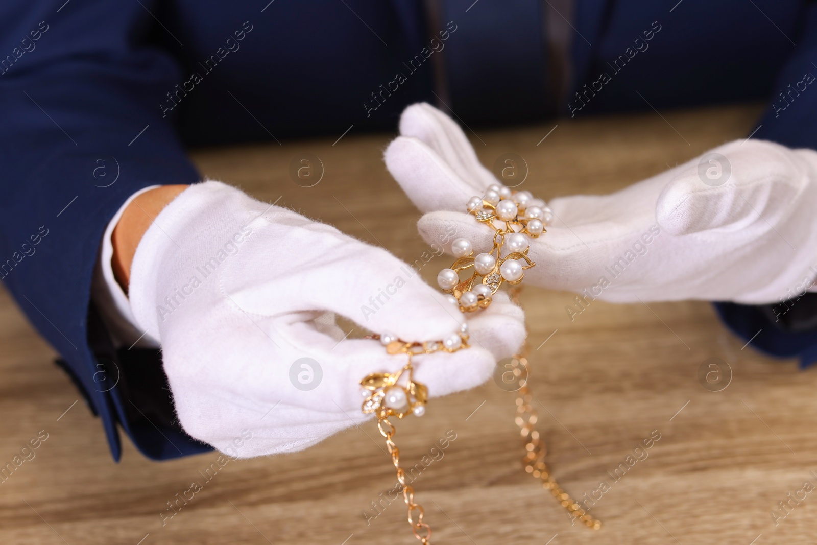 Photo of Appraiser with luxury jewelry at wooden table, closeup