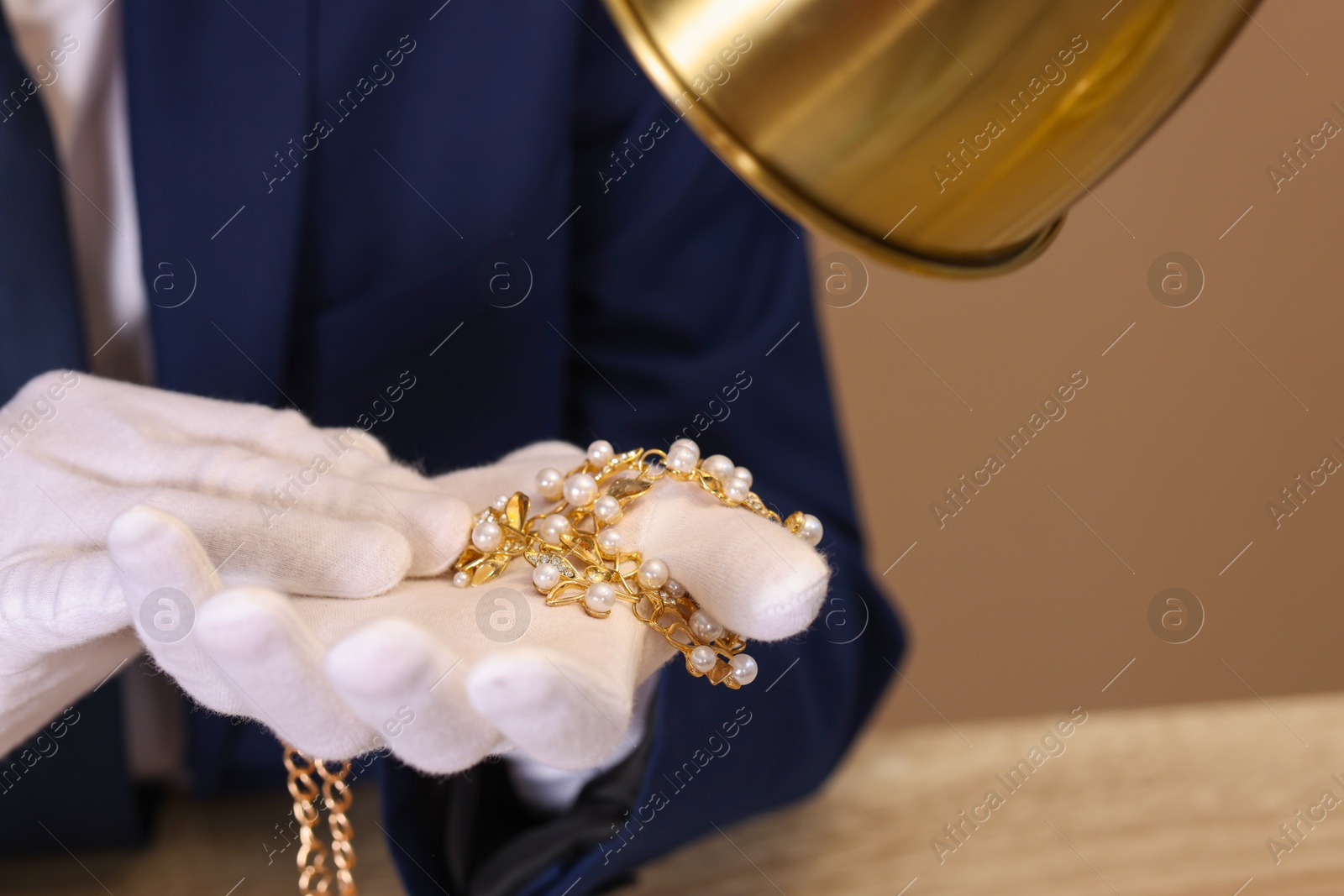 Photo of Appraiser with luxury jewelry at table, closeup