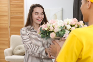 Photo of Delivery man giving gift box with beautiful floral composition to happy woman at door, closeup