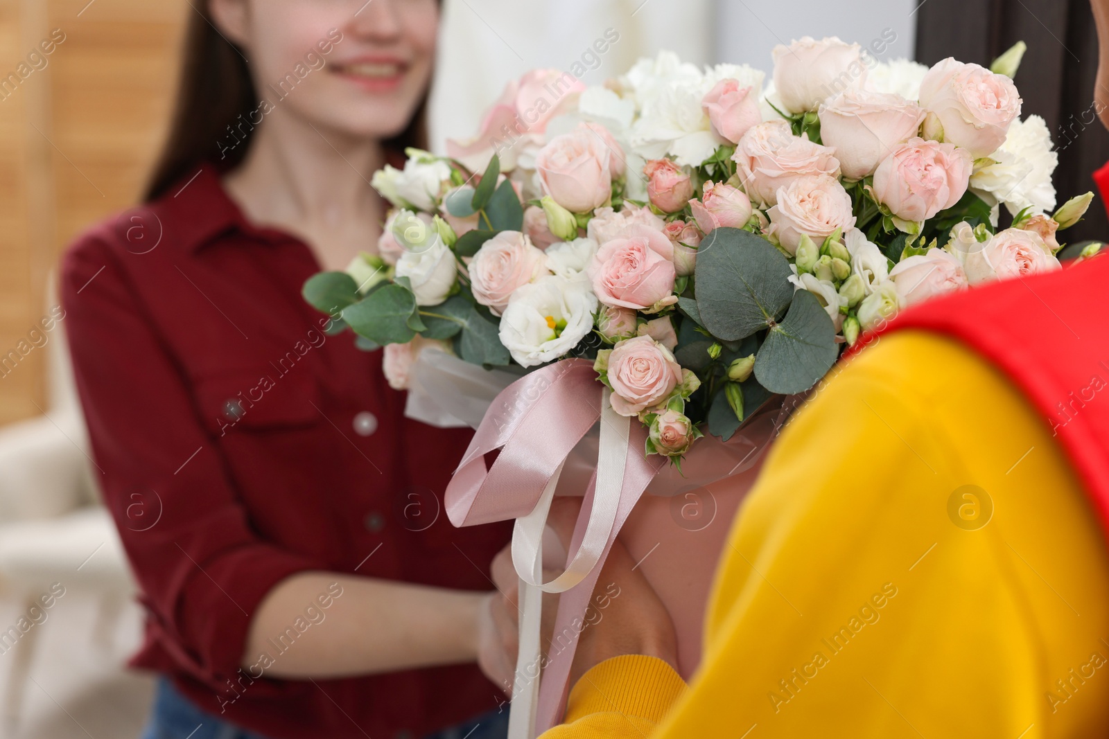 Photo of Delivery man giving gift box with beautiful floral composition to happy woman, selective focus