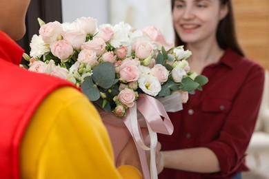 Photo of Delivery man giving gift box with beautiful floral composition to happy woman, selective focus