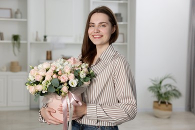 Photo of Portrait of smiling woman holding delivered gift box with floral composition indoors