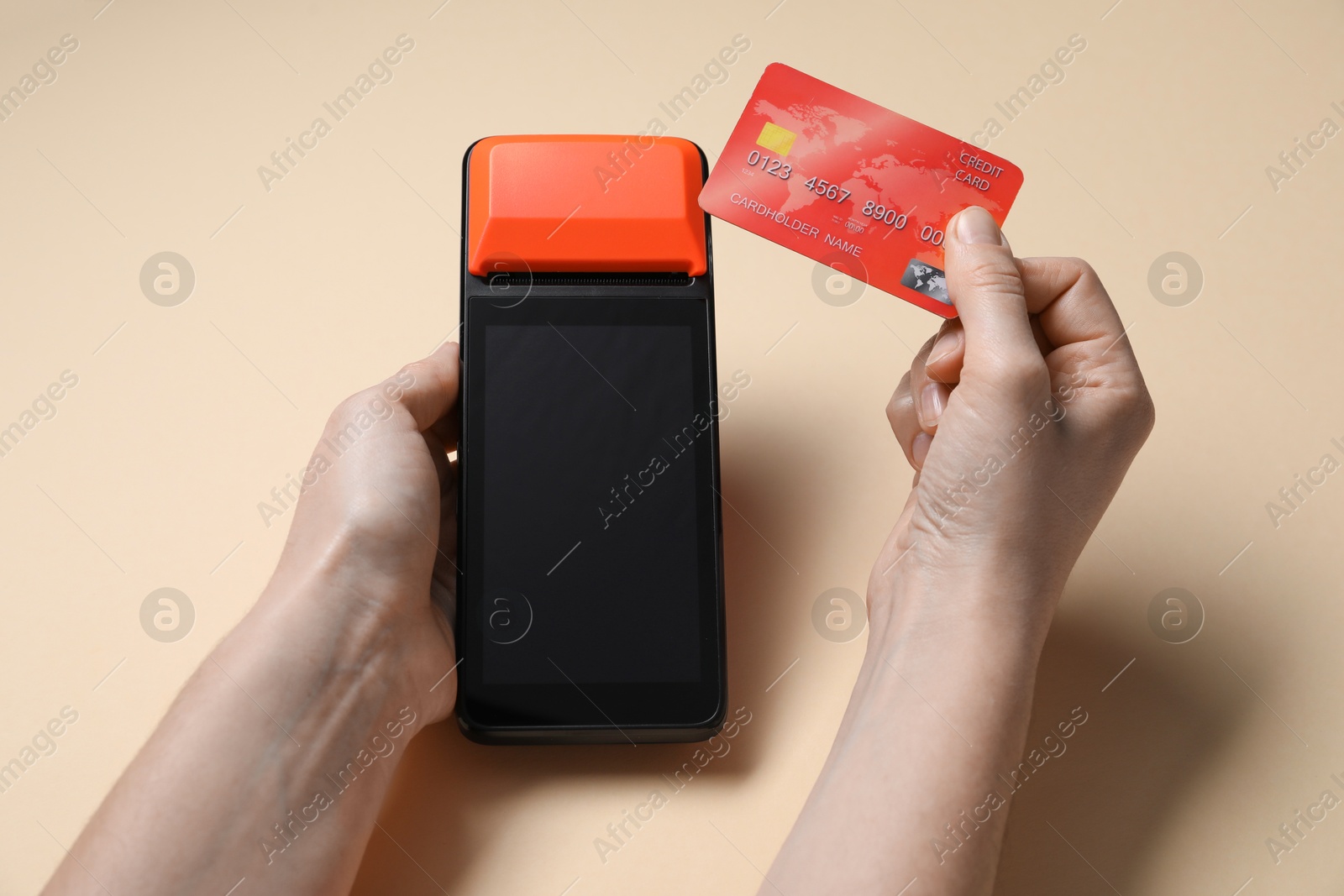 Photo of Woman with credit card using payment terminal on beige background, closeup