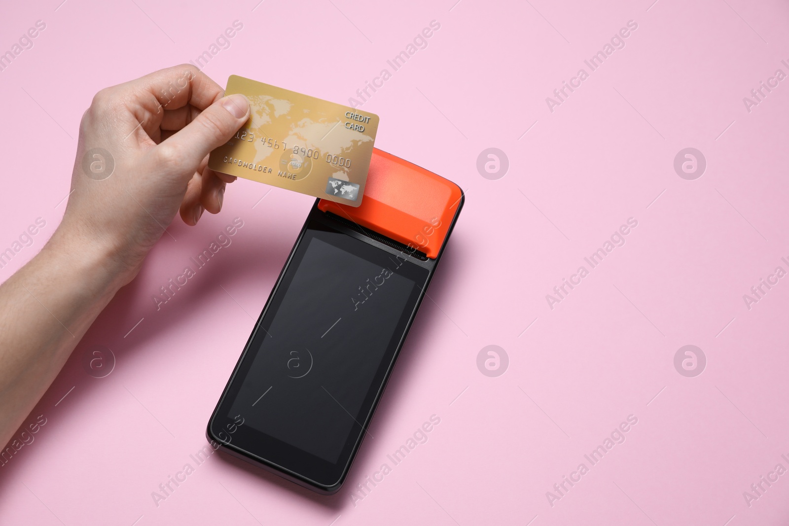 Photo of Woman with credit card using payment terminal on pink background, top view. Space for text