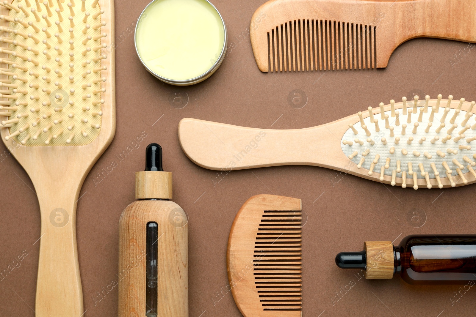 Photo of Wooden hair brushes, combs and cosmetic products on dark beige background, flat lay