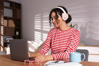 Photo of Beautiful woman working on laptop at desk in home office