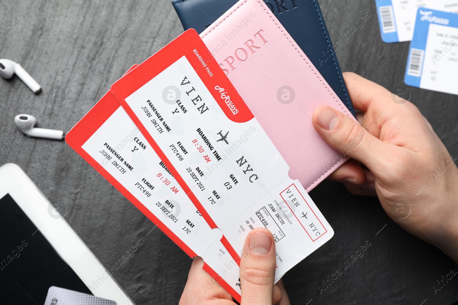 Photo of Travel agency. Man with passports and flight tickets at dark textured table, top view