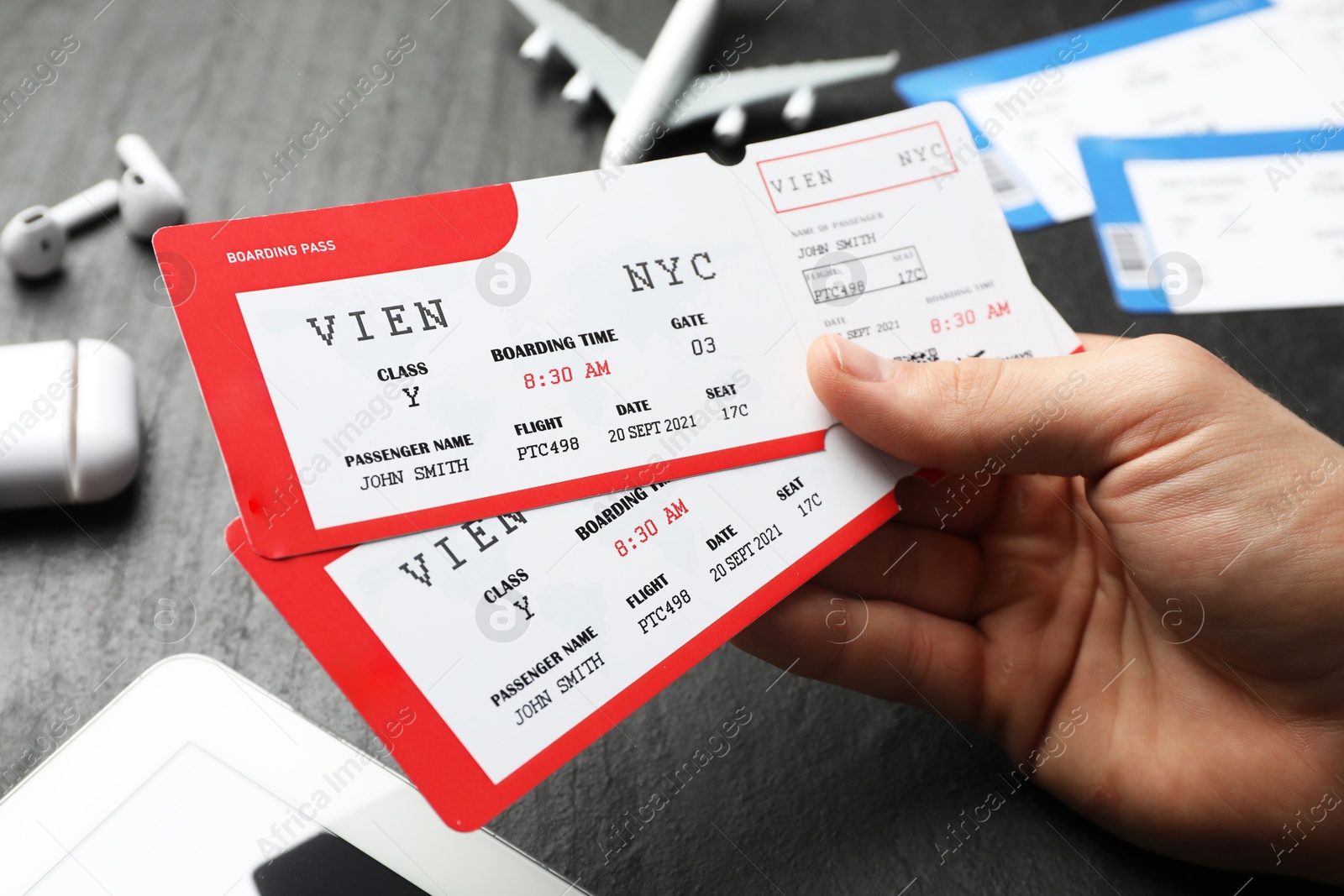 Photo of Travel agency. Man with flight tickets at dark textured table, closeup