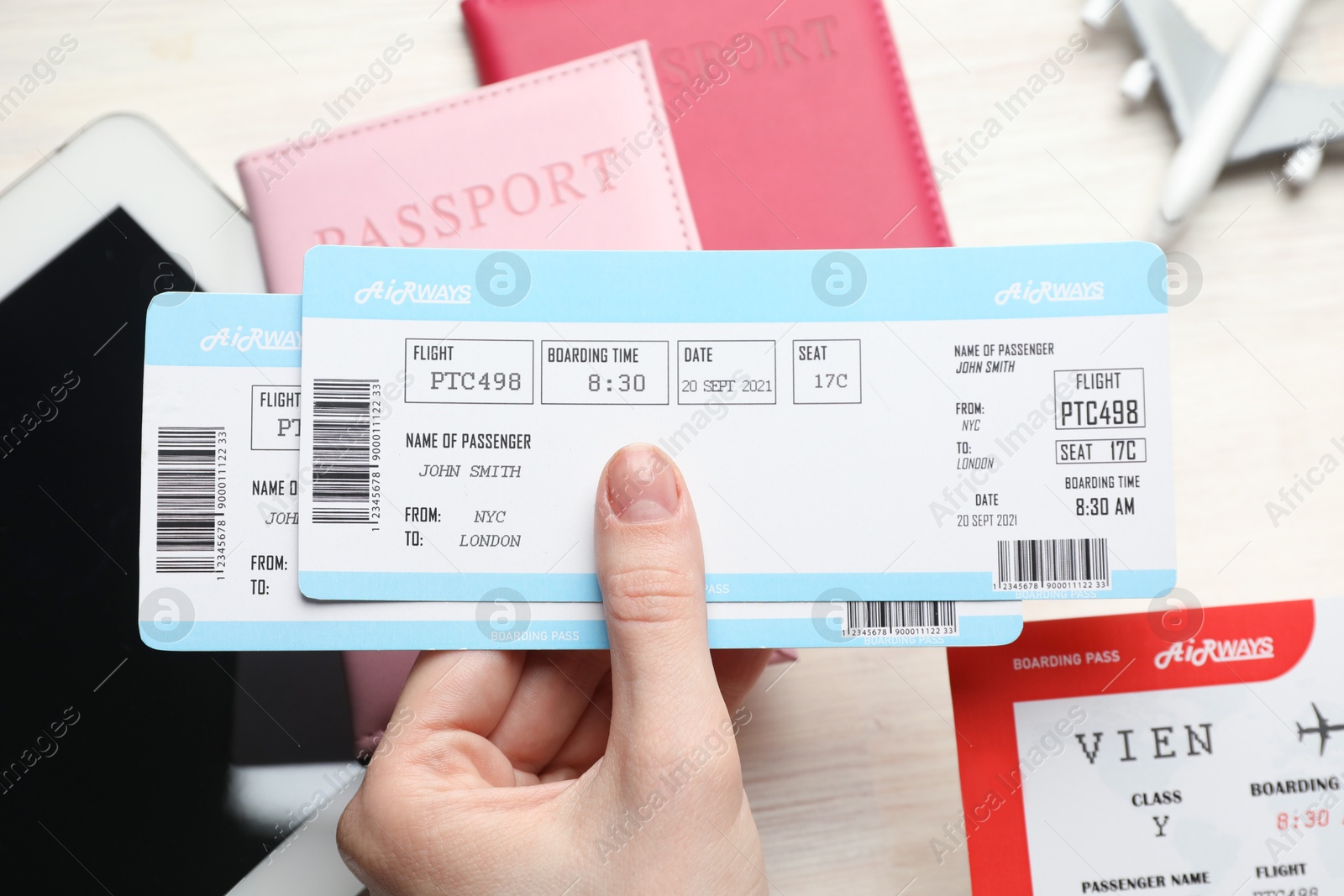 Photo of Travel agency. Woman with flight tickets at light wooden table, closeup