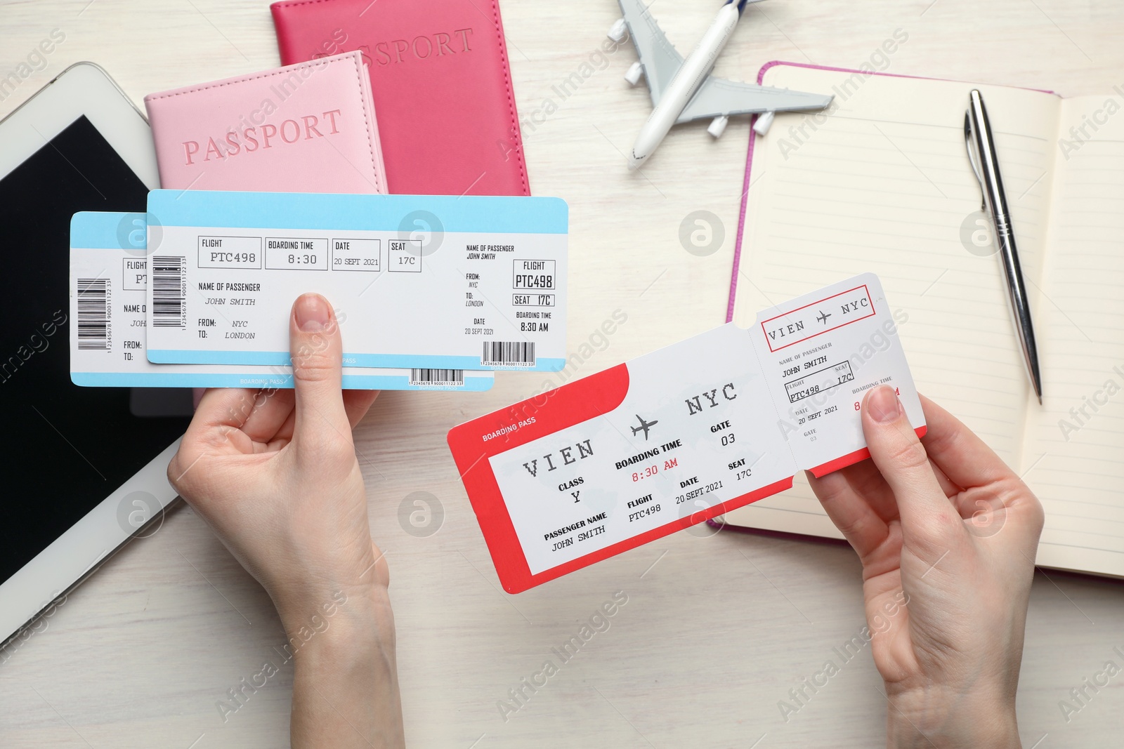 Photo of Travel agency. Woman with flight tickets at light wooden table, top view