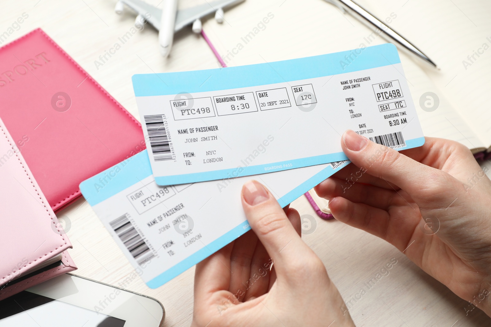 Photo of Travel agency. Woman with flight tickets at light wooden table, closeup