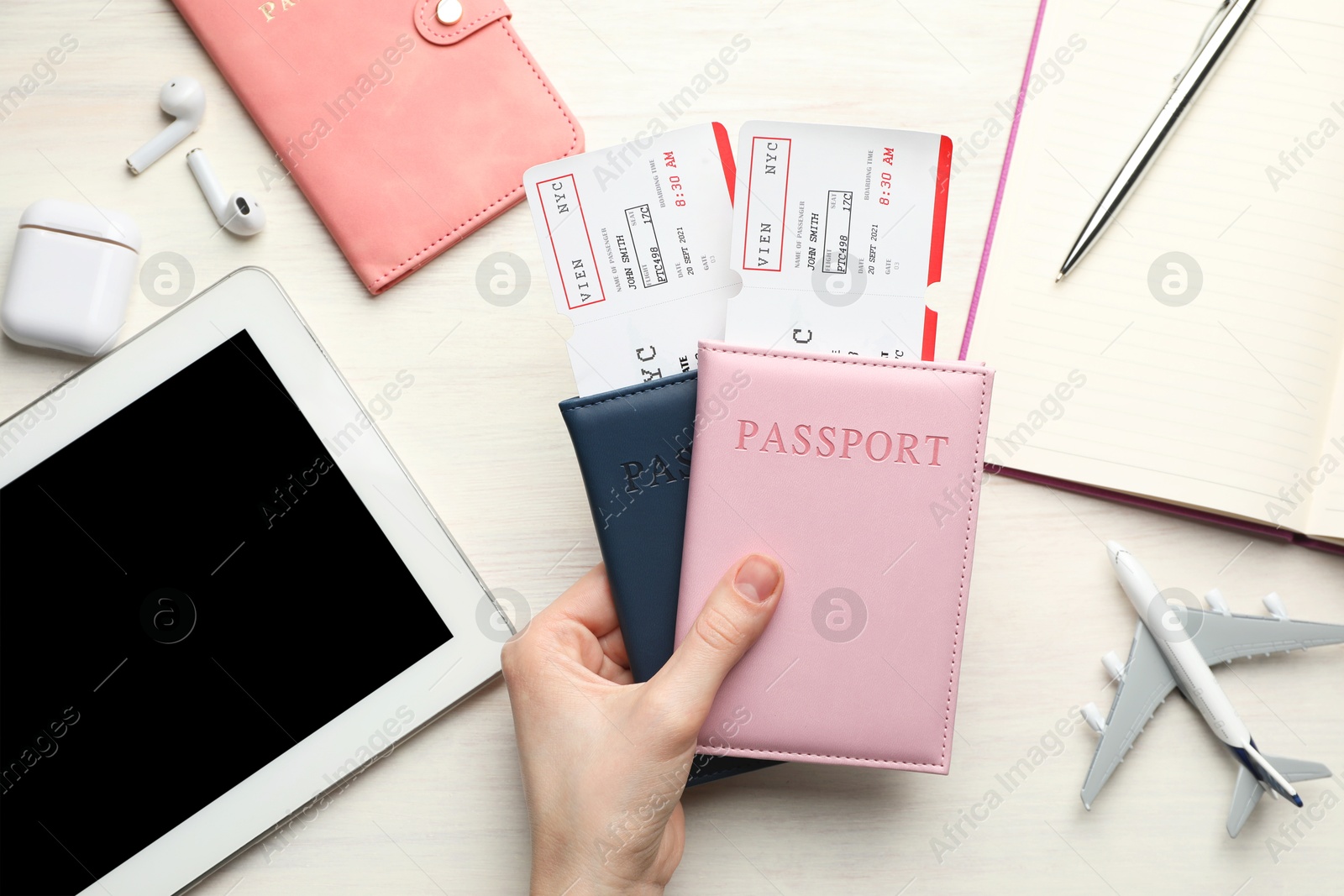 Photo of Travel agency. Woman with flight tickets and passports at light wooden table, top view