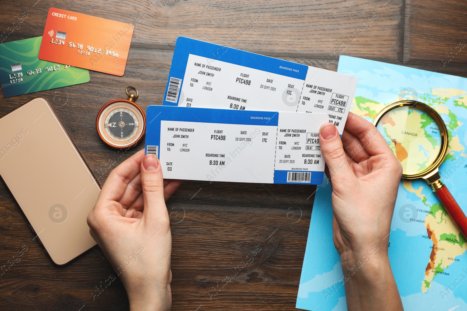 Photo of Travel agency. Woman with flight tickets at wooden table, top view