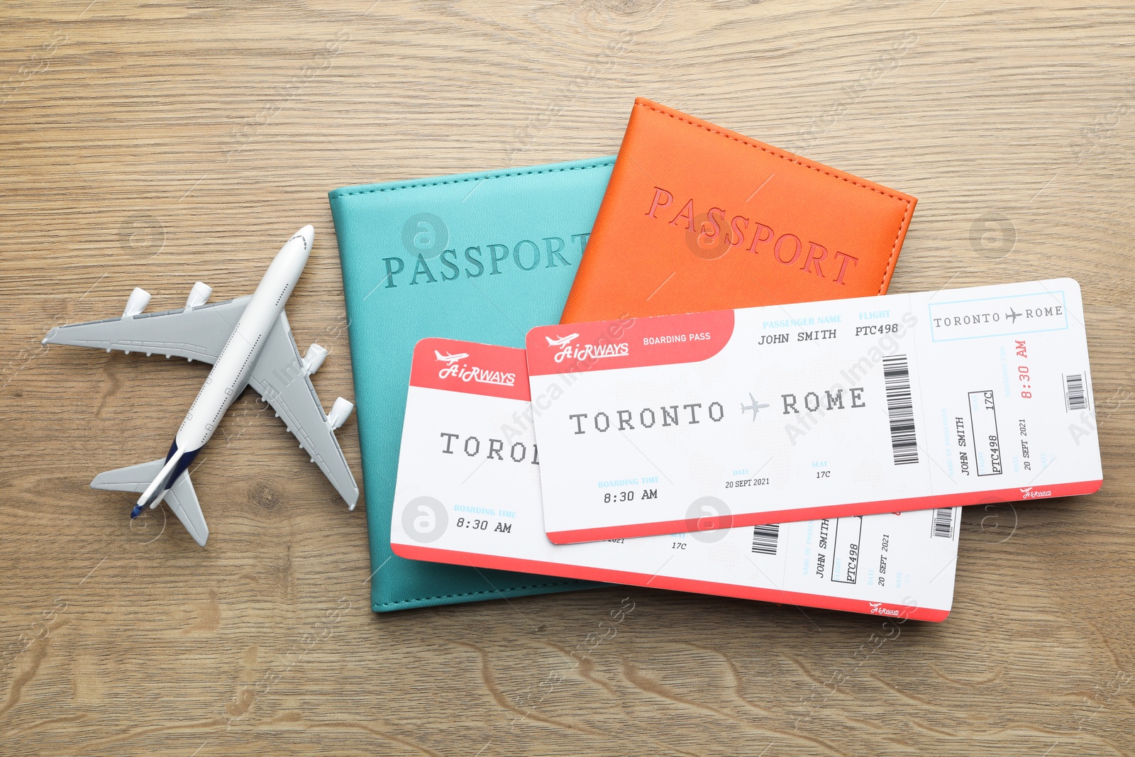 Photo of Travel agency. Flight tickets, passports and plane model on wooden table, flat lay