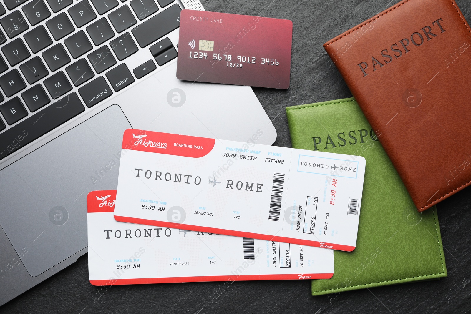 Photo of Travel agency. Flight tickets, passports, credit card and laptop on dark textured table, flat lay