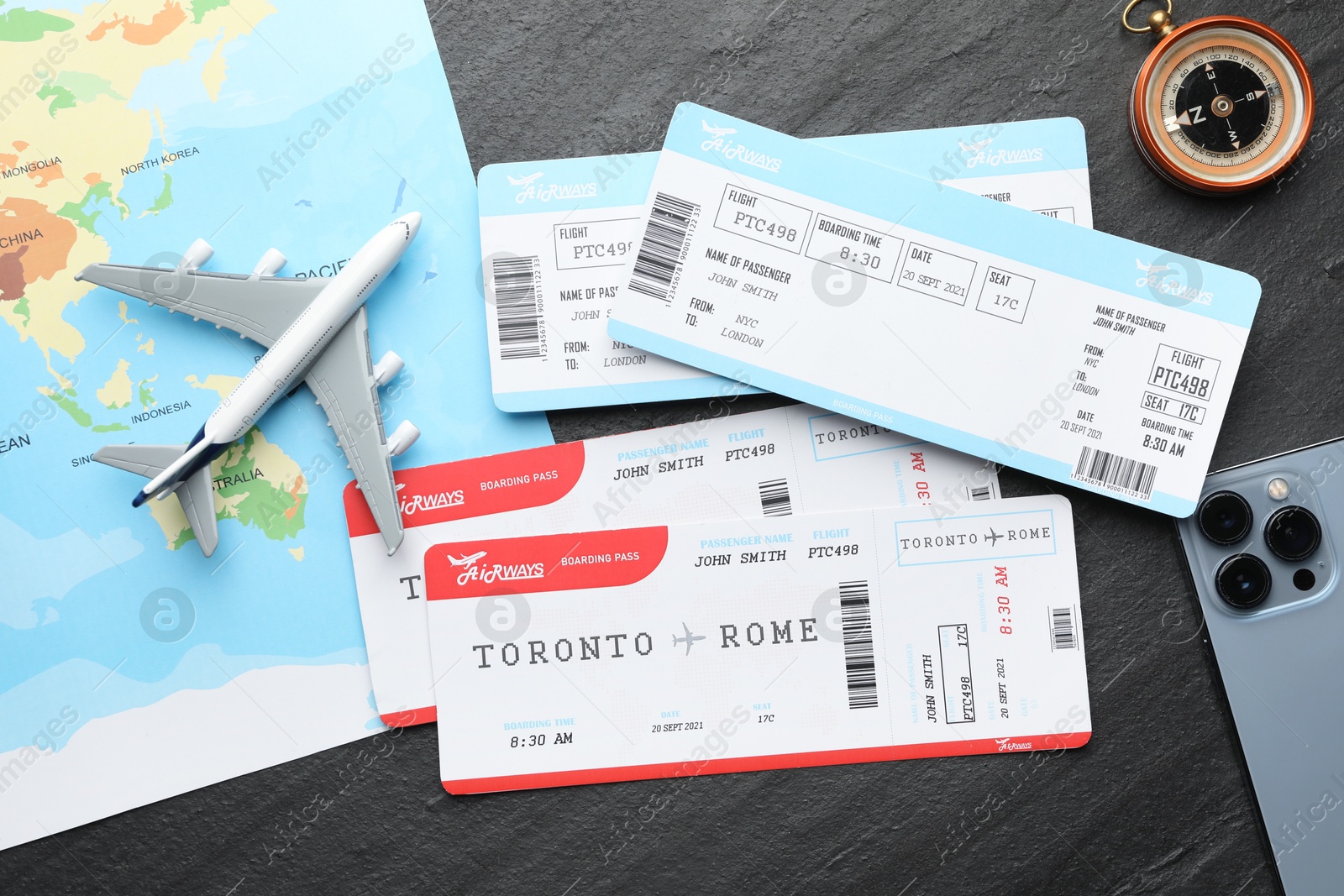 Photo of Travel agency. Flight tickets, plane model, compass and world map on dark textured table, flat lay