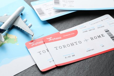 Photo of Travel agency. Flight tickets, plane model and world map on dark textured table, closeup