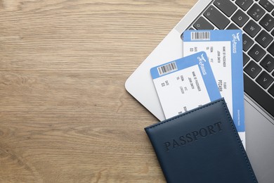 Photo of Travel agency. Flight tickets, passport and laptop on wooden table, top view. Space for text