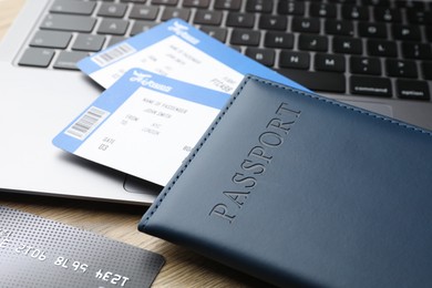 Photo of Travel agency. Flight tickets, passport, credit card and laptop on wooden table, closeup