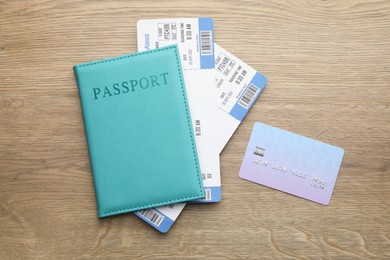 Photo of Travel agency. Flight tickets, passport and credit card on wooden table, flat lay